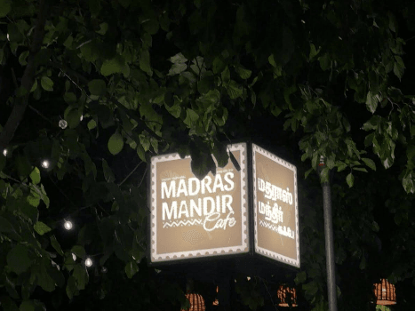 The Madras Mandir Cafe signboard lit up in the evening